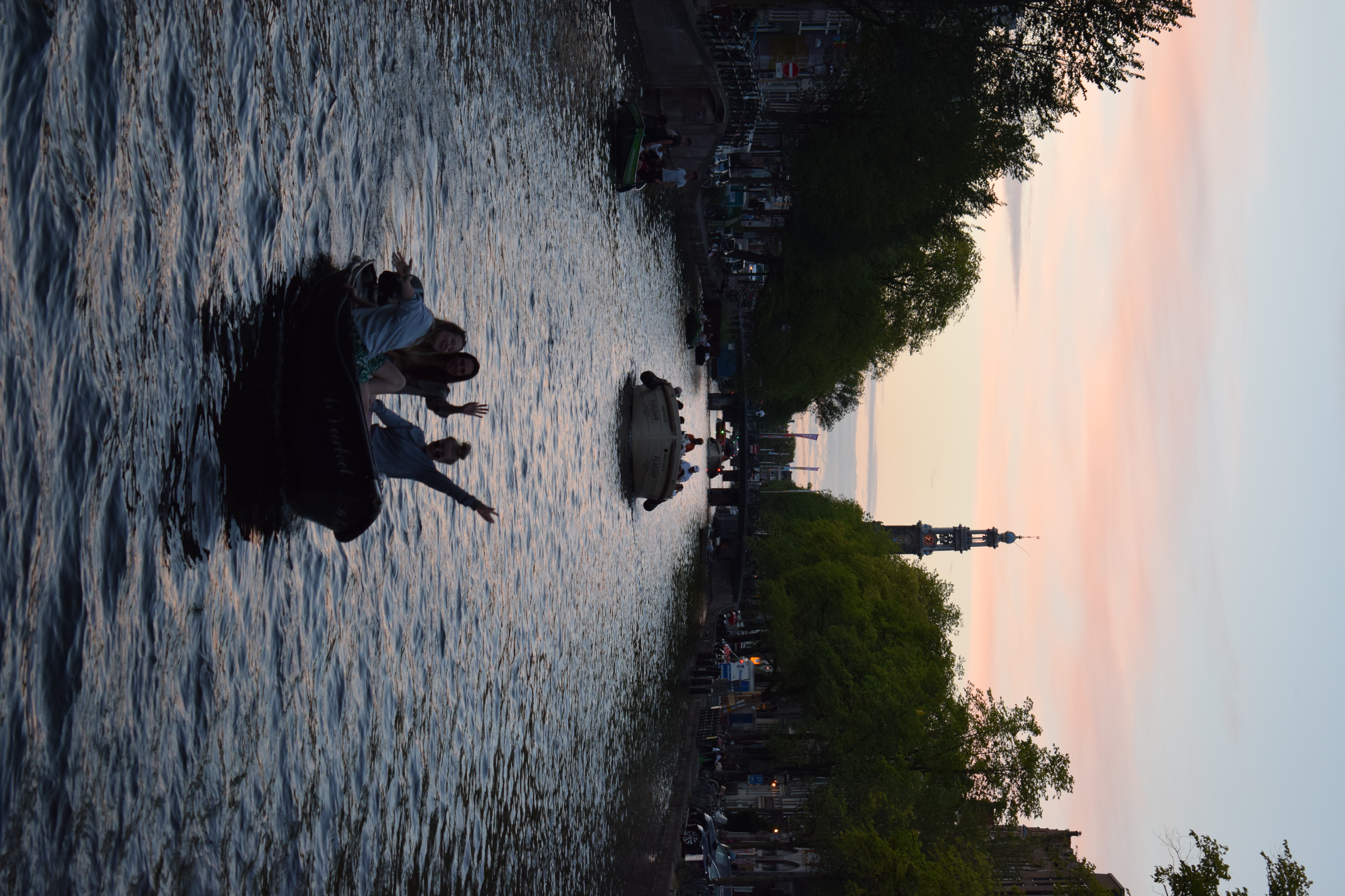 A photo I took of three people waving from a boat on a canal in Amsterdam.